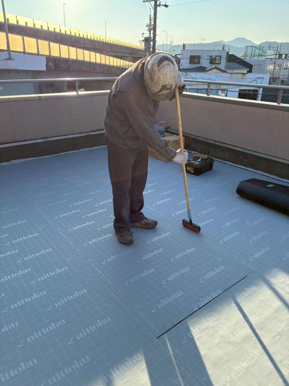 屋上の防水工事でプライマーをローラーで塗布している様子