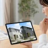 テーブルでタブレットを持つ人物が、画面に並んだ明るい外壁と暗い外壁の住宅を見比べている