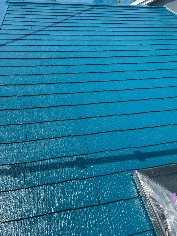 スレート屋根に仕上げ塗りを行っている様子
