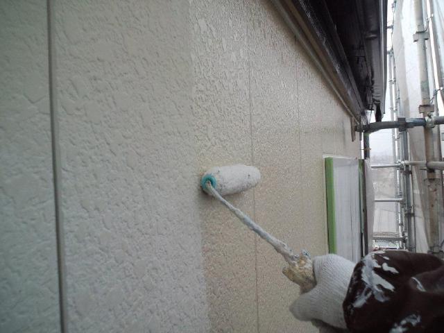 外壁へ下塗り材をローラーで塗布しています。